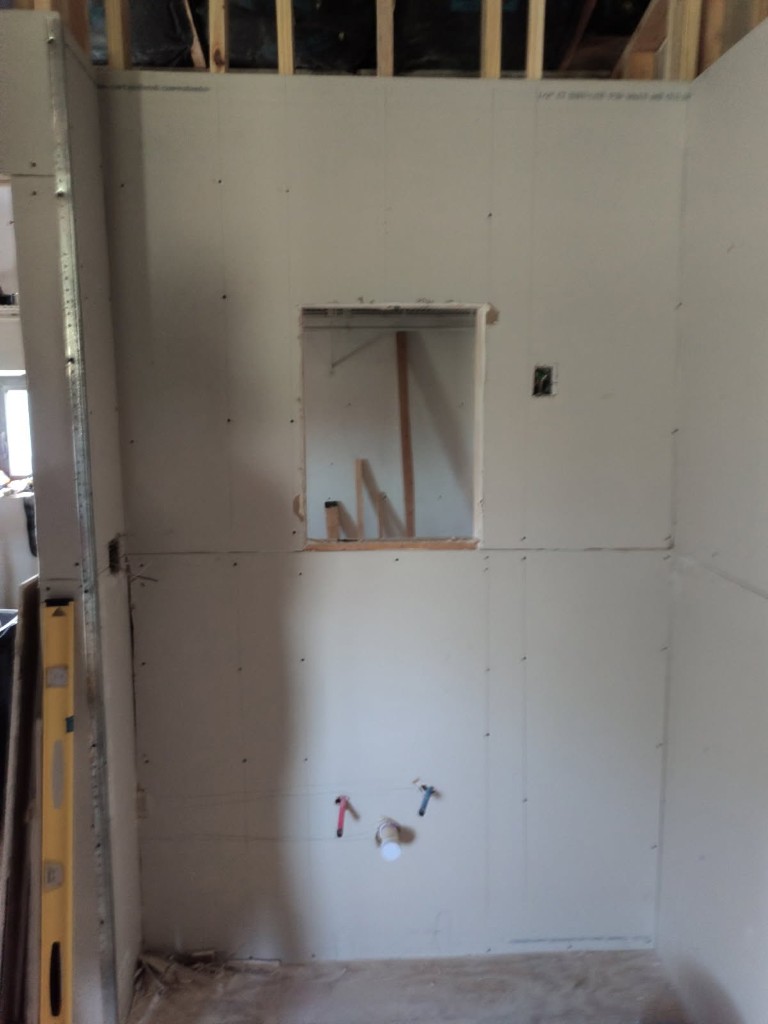 Custom shower back wall with large rectangular niche cutout in cement board and lower plumbing stubs with hot and cold caps