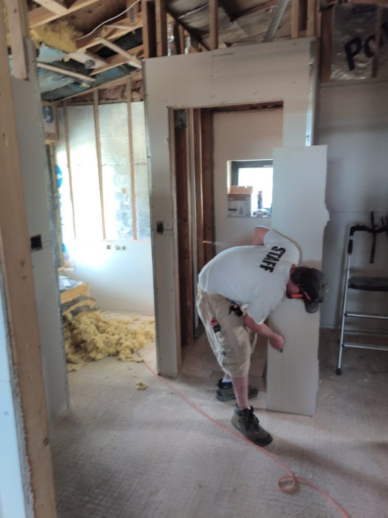 Park Avenue staff member measuring and cutting USG Durock cement board for a custom shower enclosure during bathroom renovation