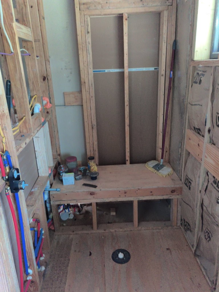 Walk-in shower wood framing with built-in bench platform and centered niche opening between studs