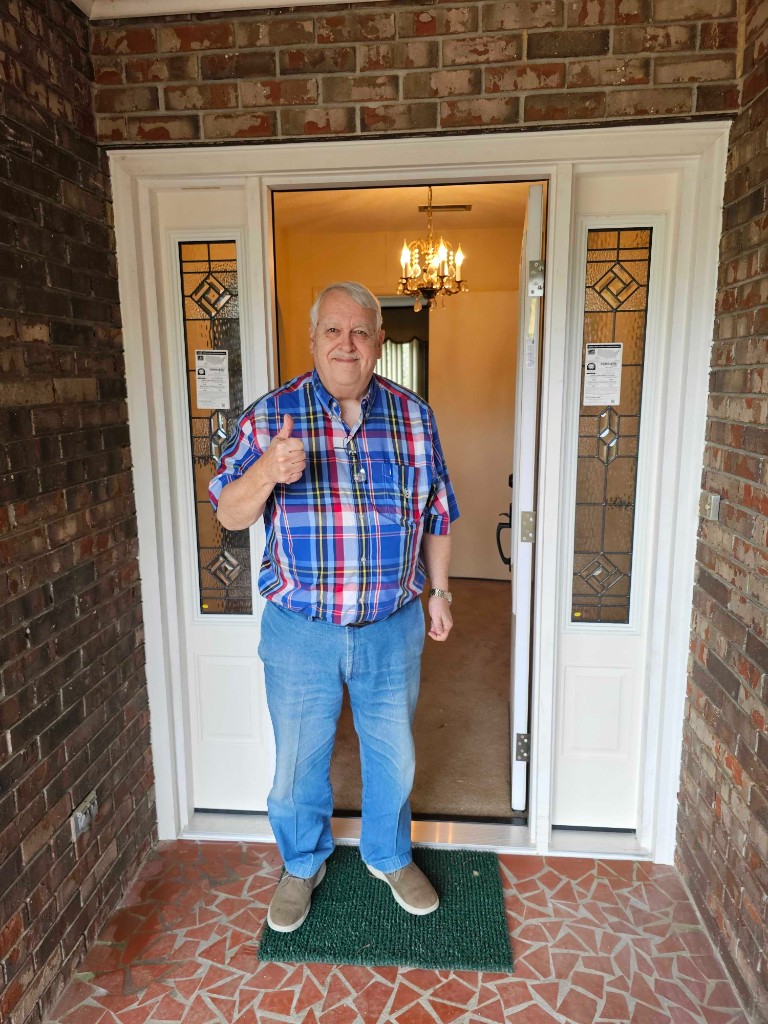 Homeowner giving thumbs up in front of a newly installed entry door with sidelights