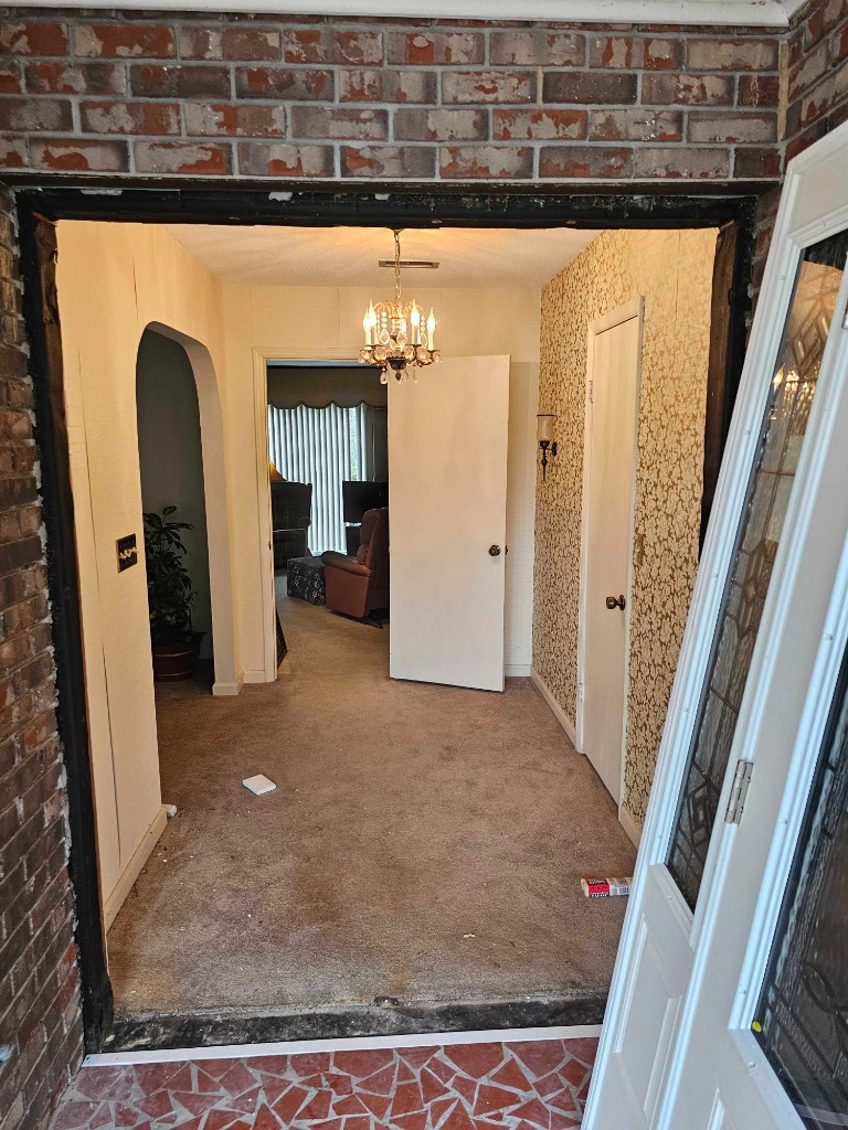 Entry door replacement in progress with new door unit staged beside a brick home