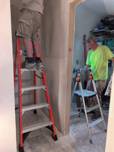 Two Park Avenue workers on ladders during a home renovation with unfinished drywall and professional installation equipment