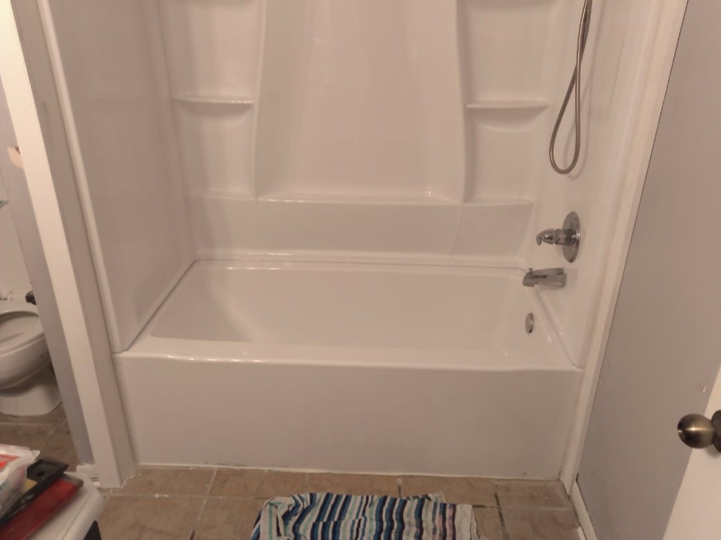 Completed white bathtub and shower surround installation front view with chrome fixtures in a clean Florida bathroom