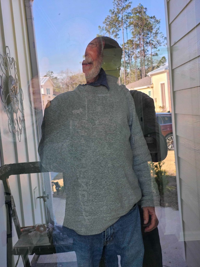 Technician finishing storm door installation with ladder and tools visible at entryway