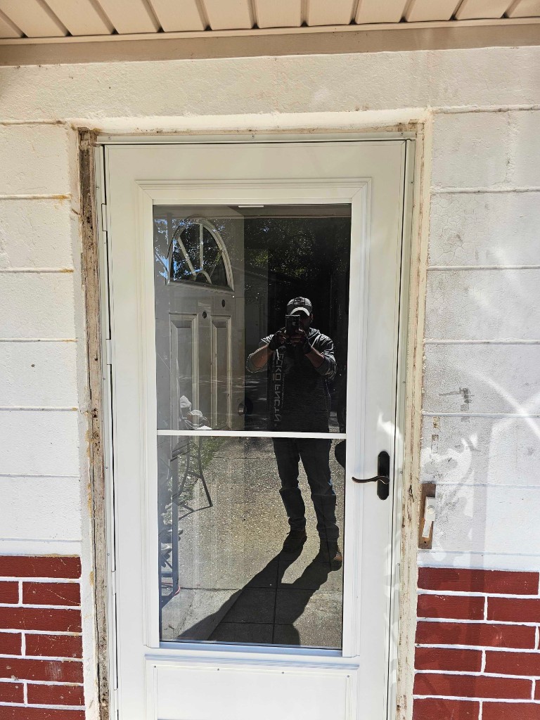 White full-view storm door installed over decorative glass entry door