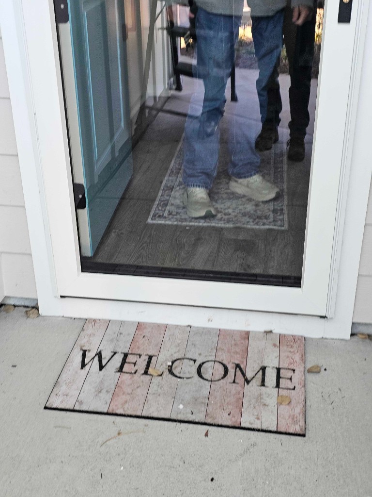 White storm door with welcome mat at a residential entryway